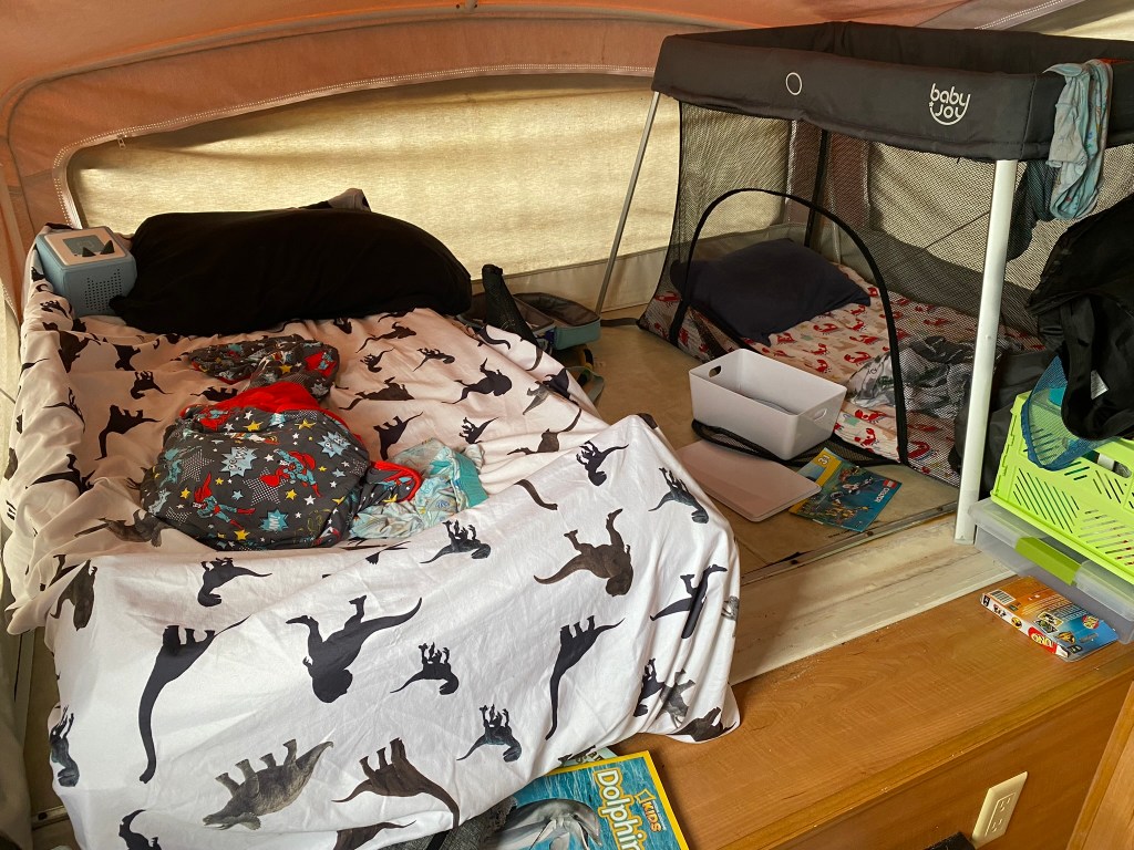 Child cot and pack and play set up in a camper.